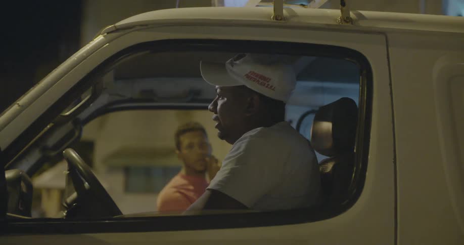 A man in a white hat backs up a van