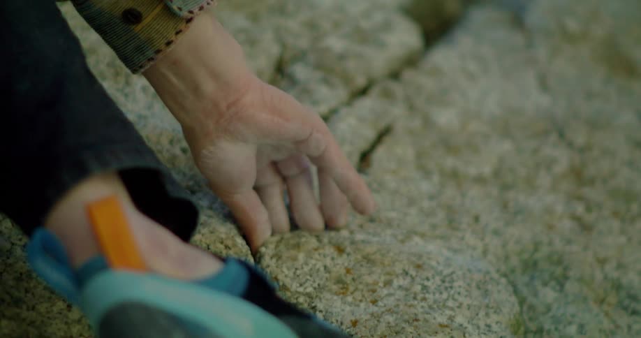 Female rock climber uses crevices as perches while climbing a rock face