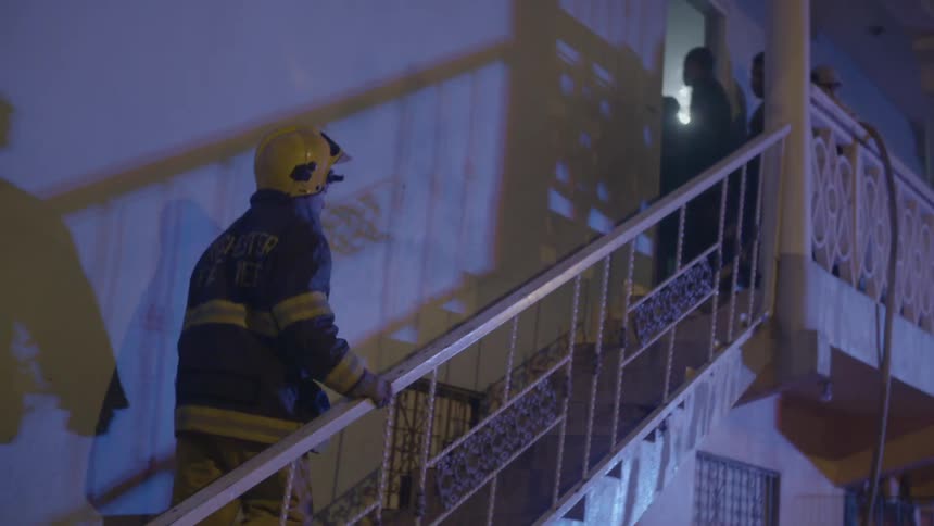 A firefighter walks up apartment stairs