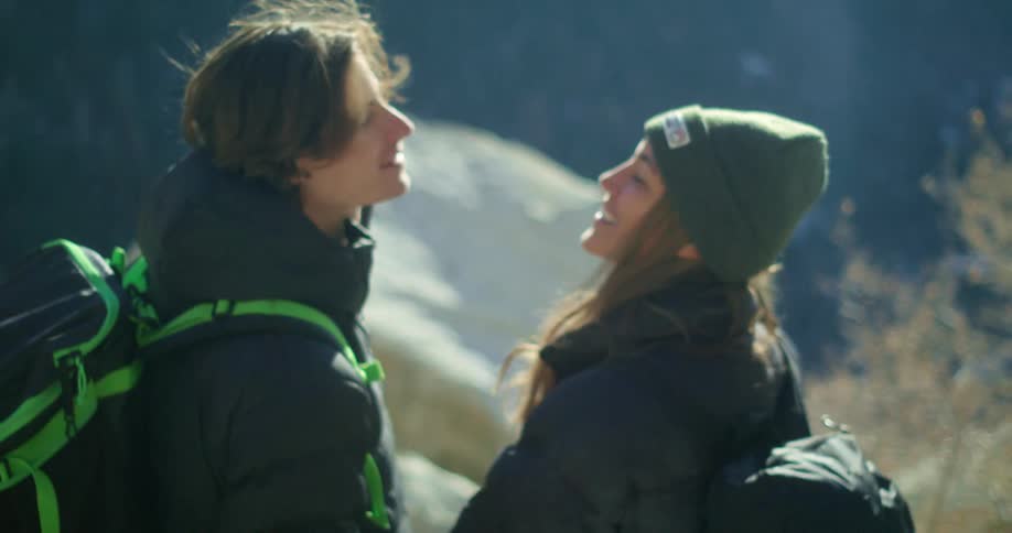 A couple shares a kiss while hiking in a scenic mountainous area