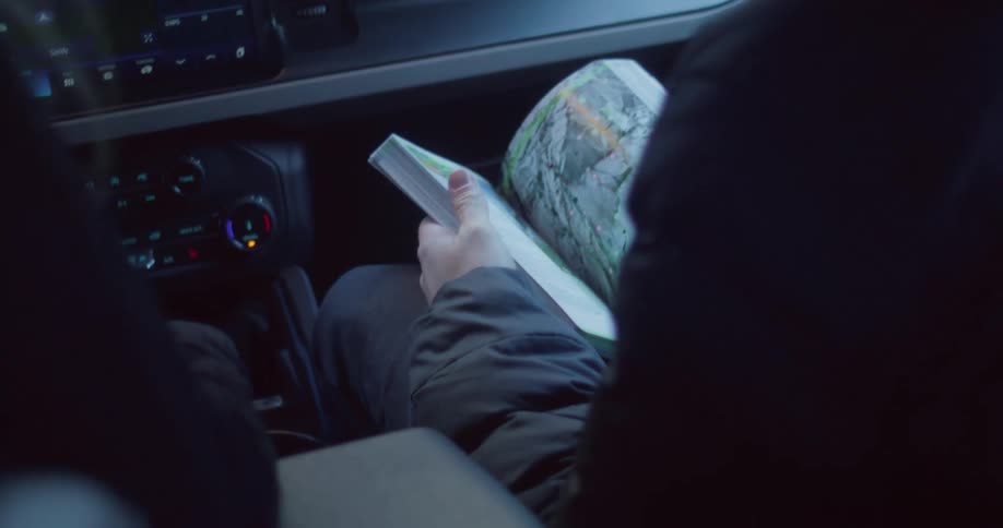 Person holding an open map inside a moving car