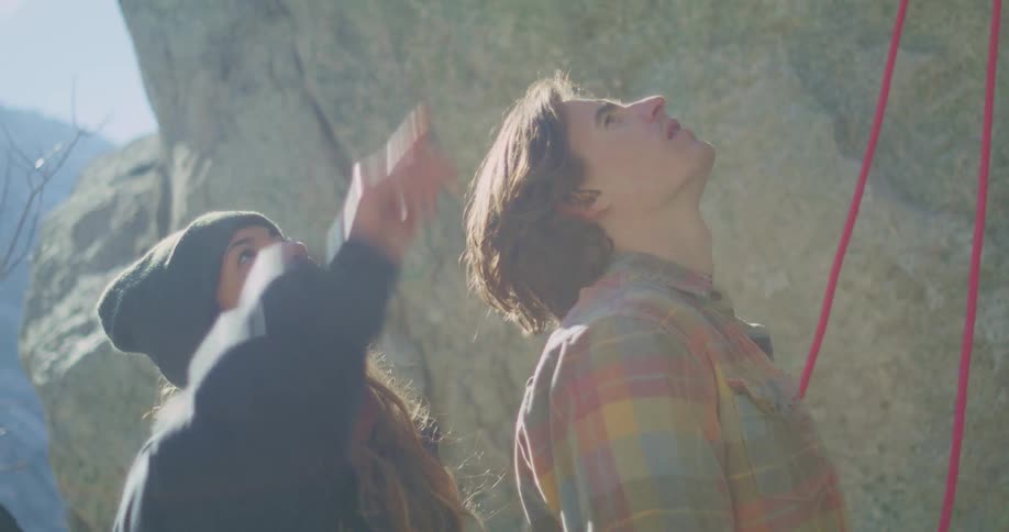 Two climbers look and point at the rock wall before the ascent