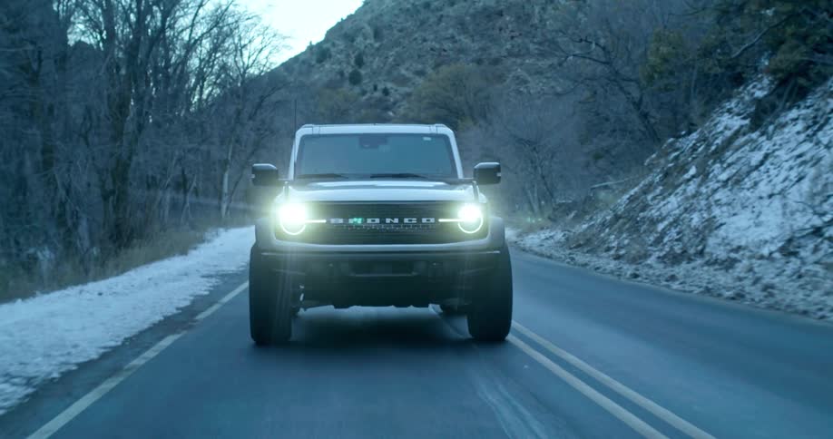 A rugged suv drives down a mountain road in winter