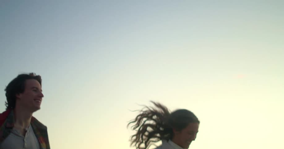 Smiling couple running hand in hand at sunset
