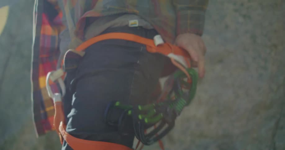 A man progressively slips a rock climbing harness around his legs