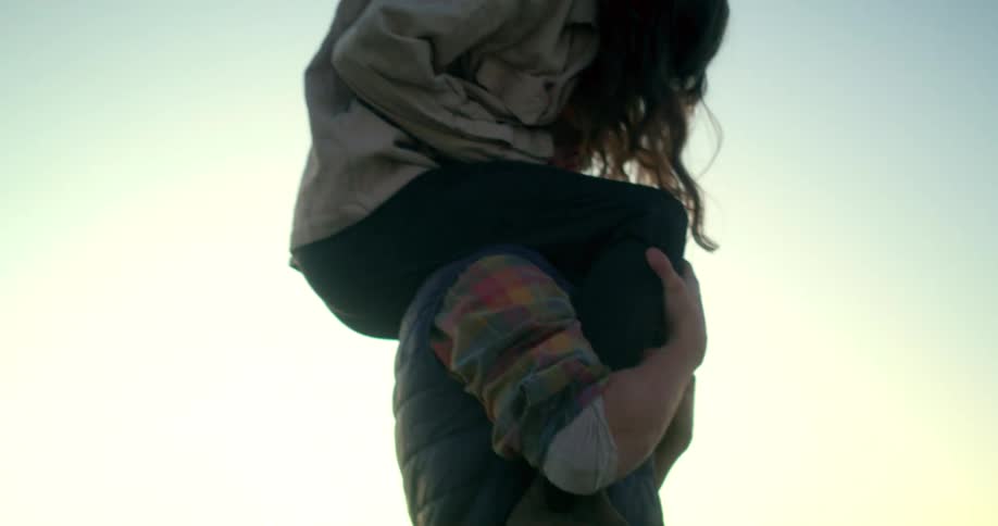 A man giving a woman a piggyback ride showing them laughing in a vast open field