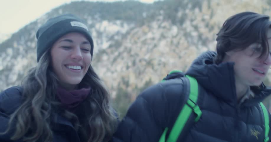 A couple walks in a snowy mountain setting