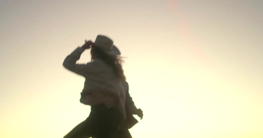 Happy couple dancing in a field at sunset in the country