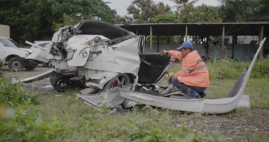 Man inspecting a drastically mangled remains of a vehicle wreckage