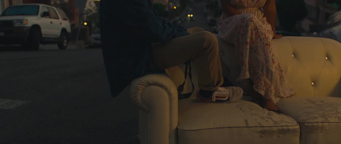 Couple sitting on a couch placed in the middle of the street at dusk