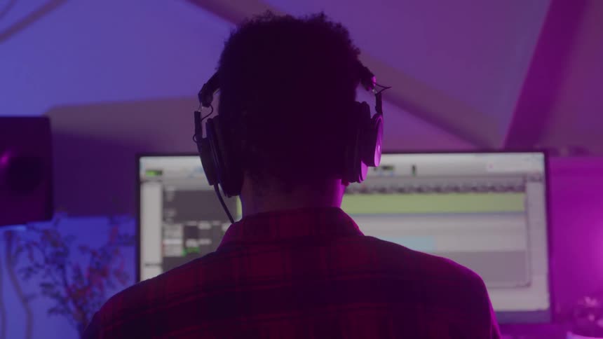 A person works on audio production in front of a computer screen