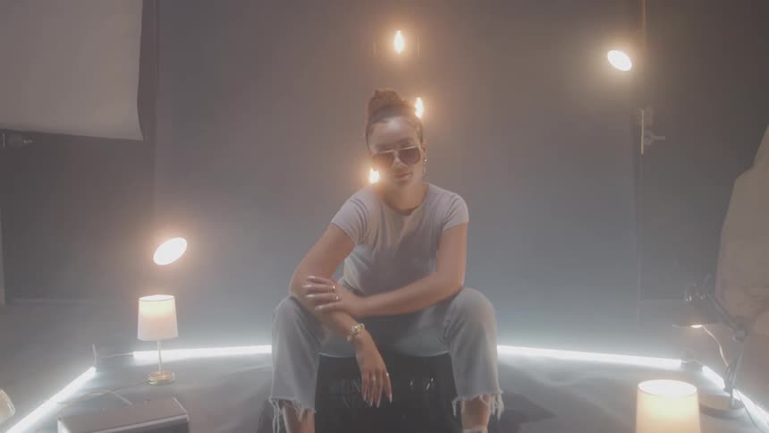 The model is posing on a lit stage