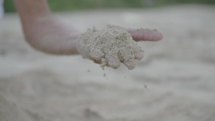 A person is tossing sand in their hand