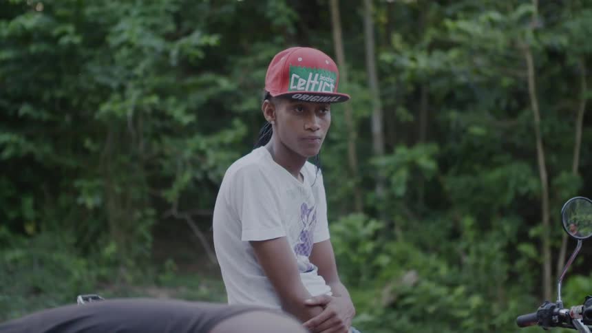 A man in a hat sits on his bike near the woods