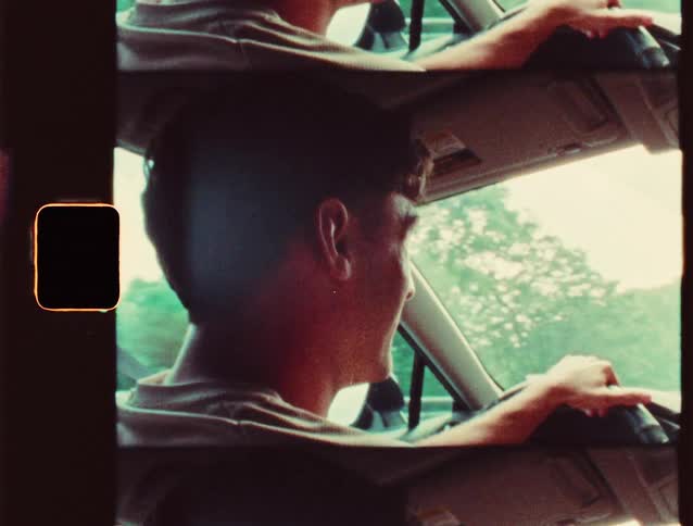 A man drives with a smile as sunlight streams through the window