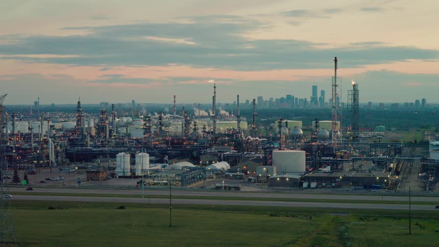 An oil refinery with smokestacks and tanks at dusk