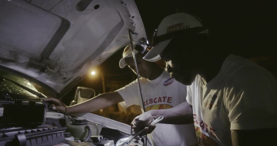 Two men look under the hood of a van