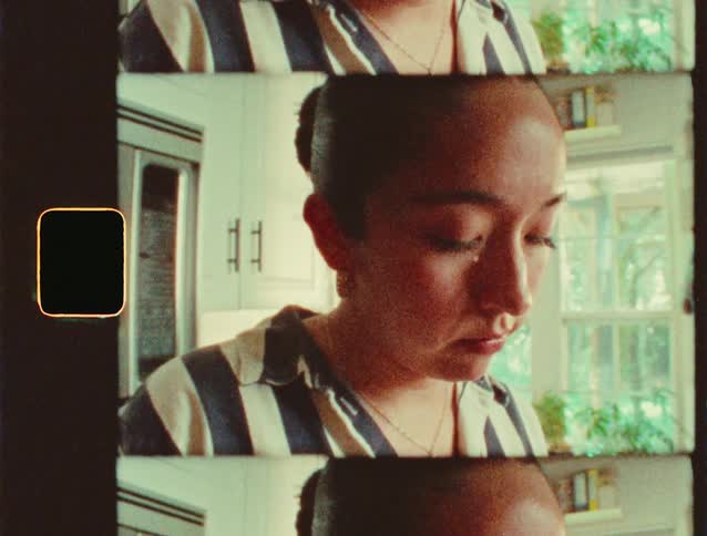 A woman with her head down appearing to be in deep thought within a kitchen setting