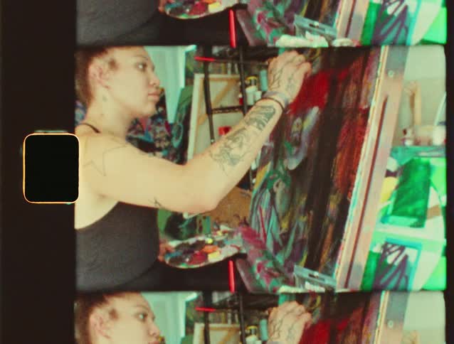 A artist is painting on a canvas in their studio
