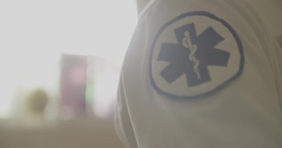 A person with a medical patch on their shirt stands outside