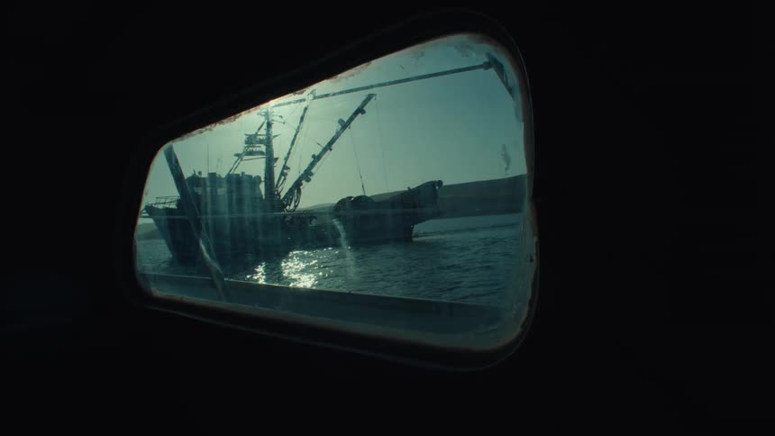 A boat on the lake is seen through the window of another boat on a sunny day in the ocean
