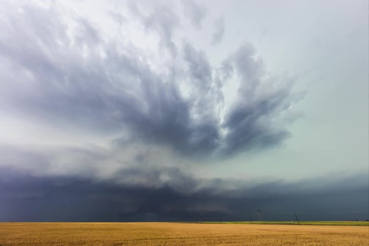 Dark storm clouds form dramatically over open farmland