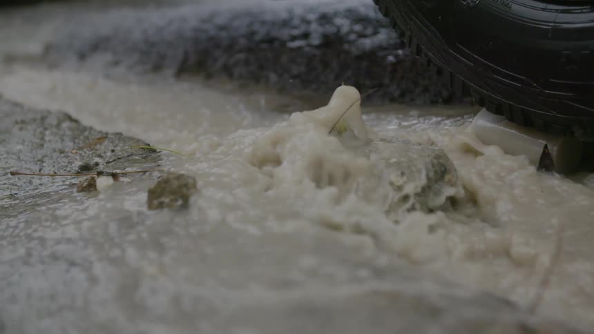 Water gushes over stones beneath a tire