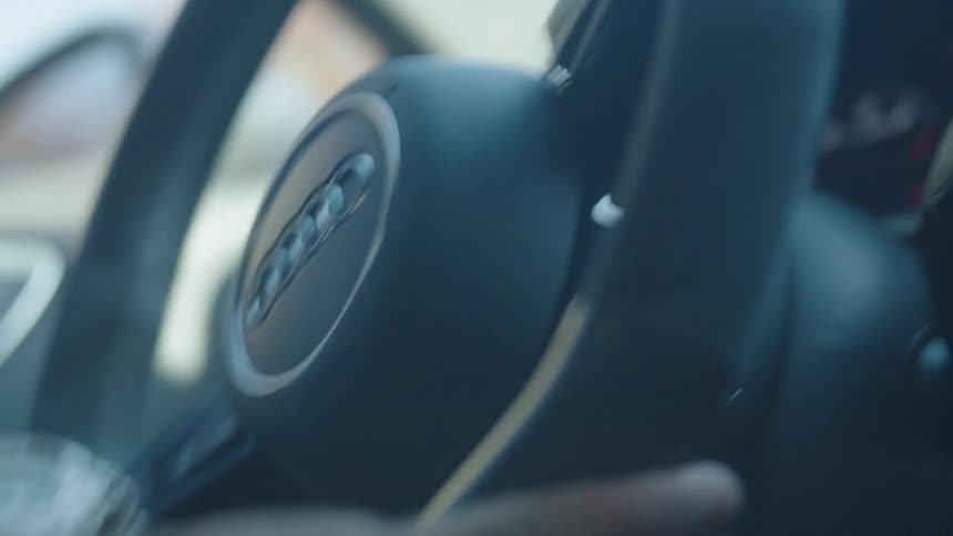 Hands hold the steering wheel of a moving audi car