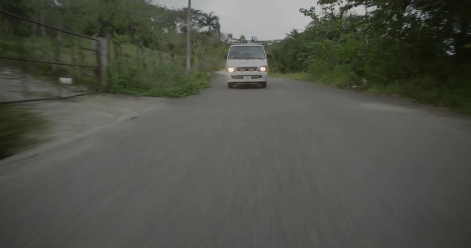 Emergency vehicle driving fast down road on overcast day