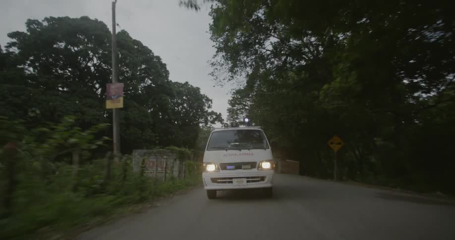 An ambulance is driving fast down a rural road