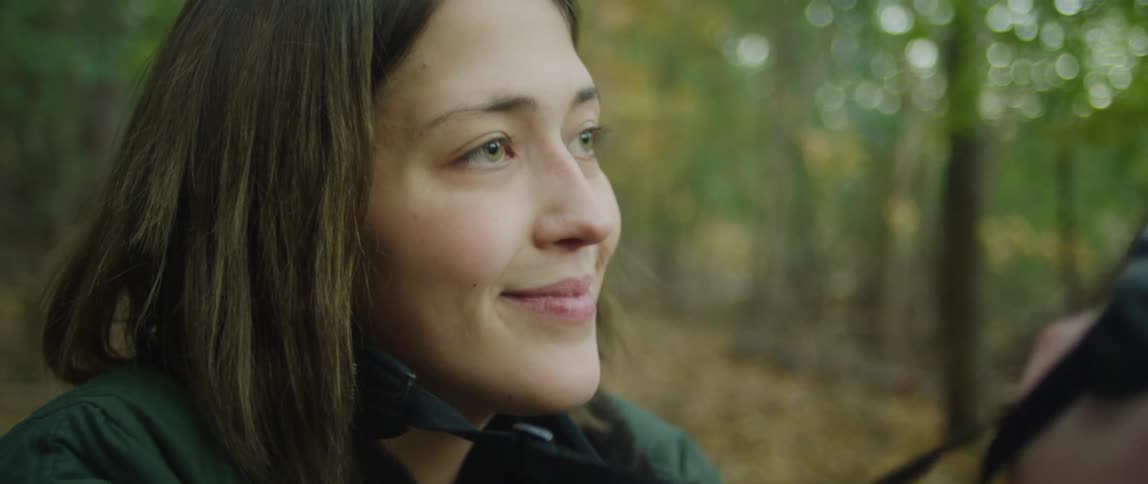 A woman smiles while photographing in a forest
