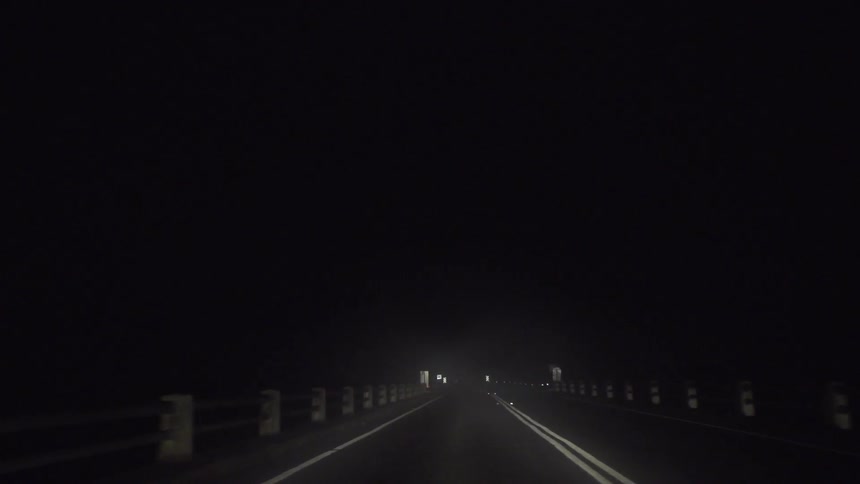 Vehicle driving down a dark road at night