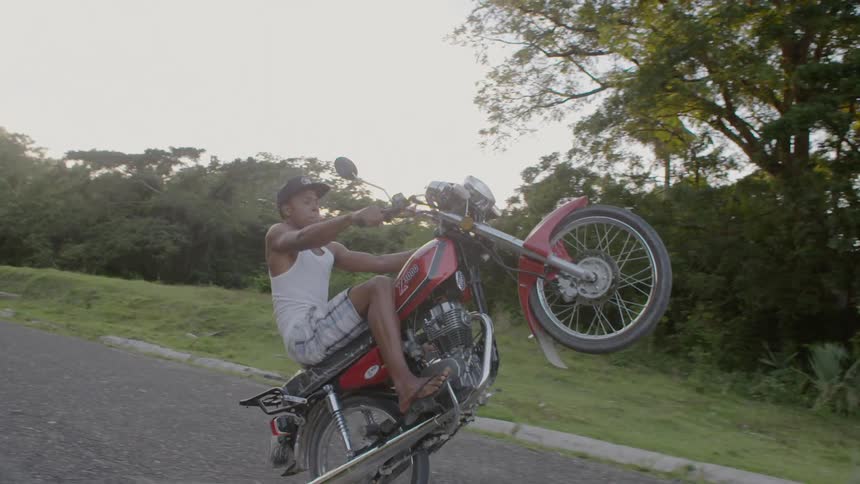 A man on a motorcycle does a wheelie