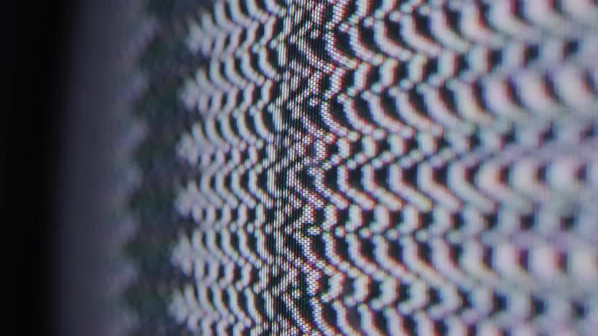 A video shows a closeup shot of a television screen with a lot of static and some colorful interference the screen shows black and white noise with some bars of color appearing and moving across the screen