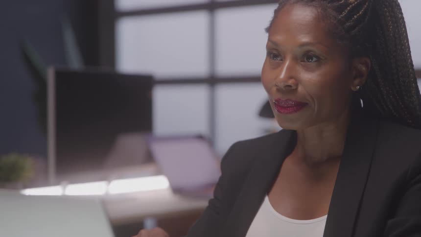 The worker is smiling while using her laptop