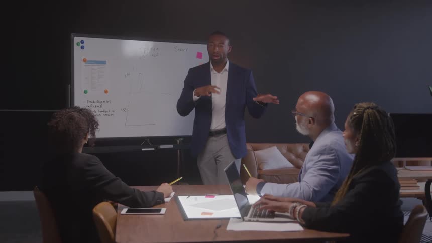 Man standing talking to three other people in an office room