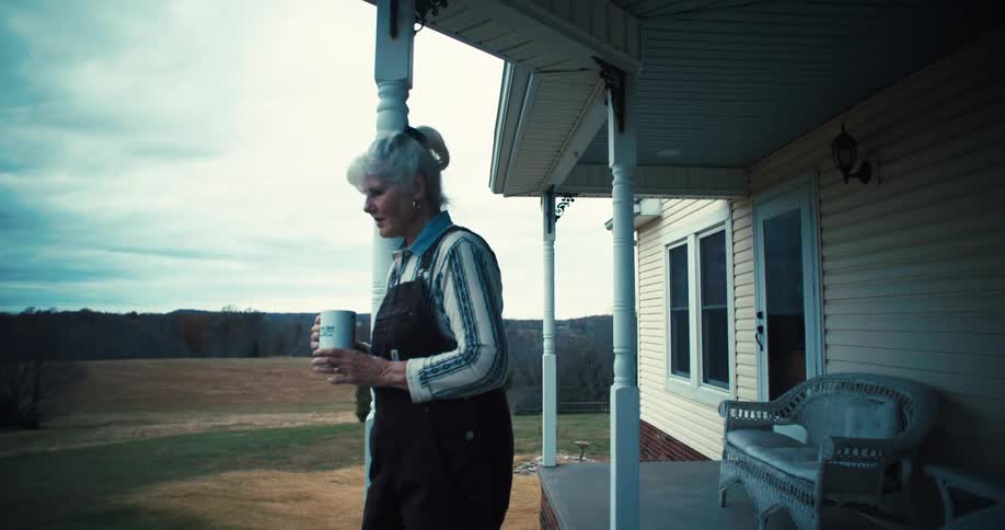 The woman is drinking coffee on her porch