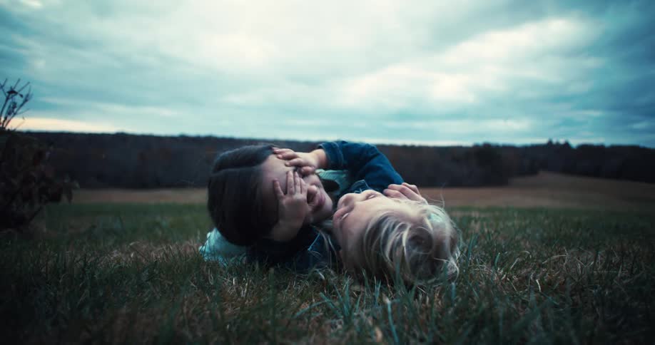 Two children sitting on the grass outdoors playing together