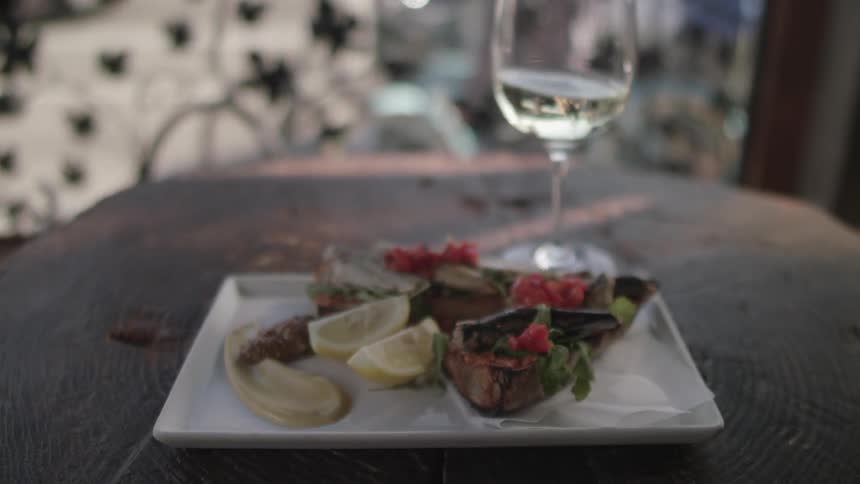 Person sets wine glass on outdoor table next to plate with food