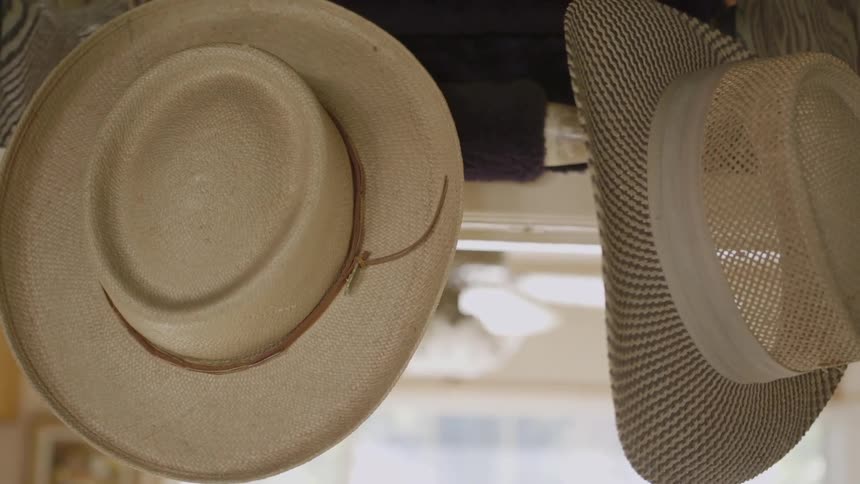 Hats are hanging from the wall as a ceiling fan spins