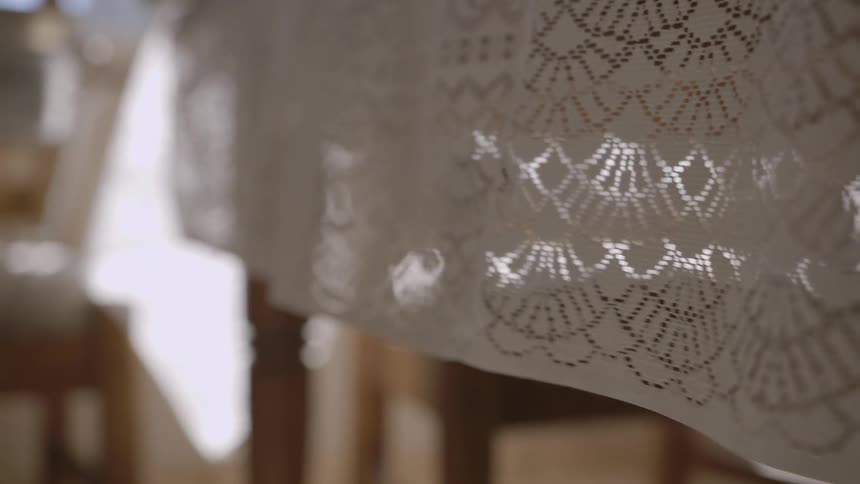 A tablecloth is draped over the side of a table and moves and billows