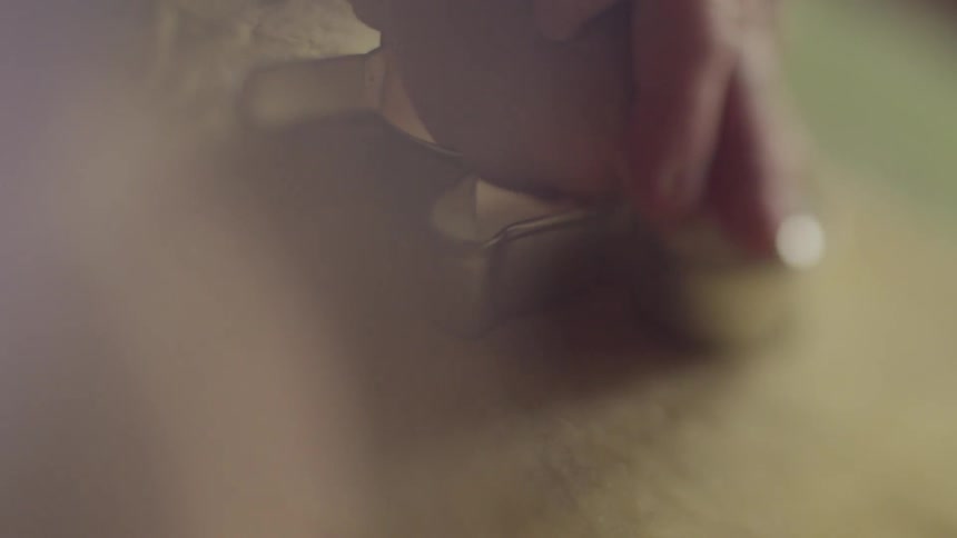 Person pushing cookie cutter into flat dough