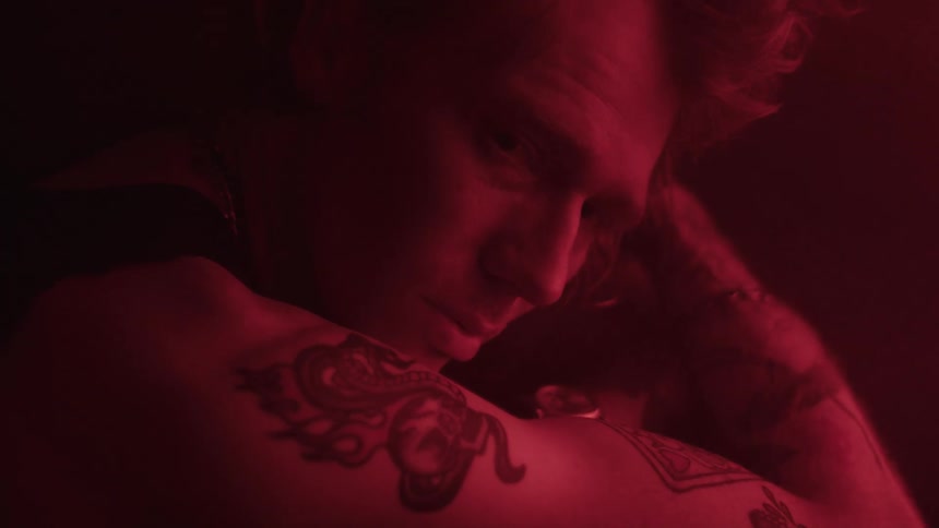 Tattooed man staring intently under red light