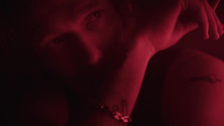 Man smokes while in an area dimly lit by colored lighting