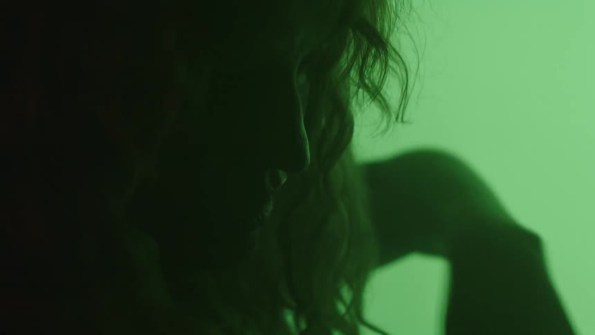 Face in profile shadowed against a background lit by green light