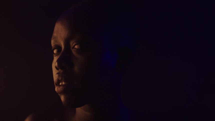 Face lit by warm light in contrast with a dark background