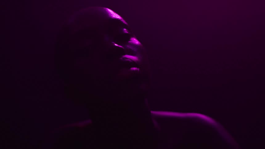 Person in silhouette lit by pink light in a dark setting