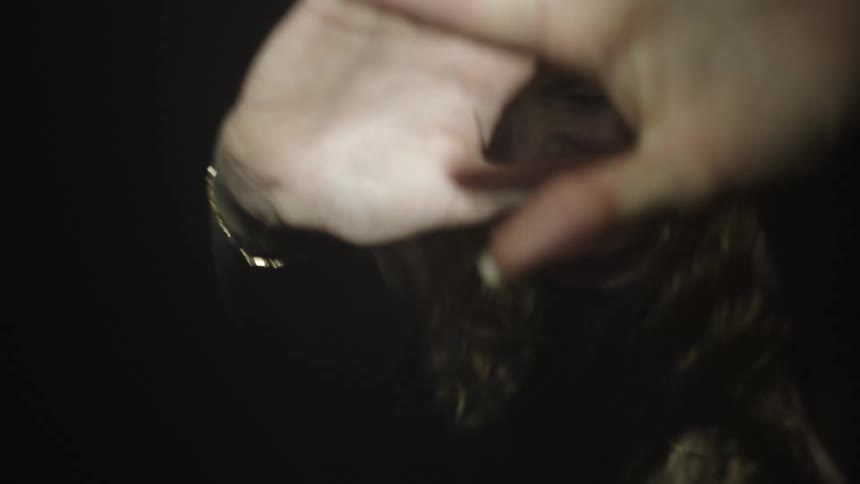 Blonde woman yells while shielding her face from the bright light shining on her in a dark area