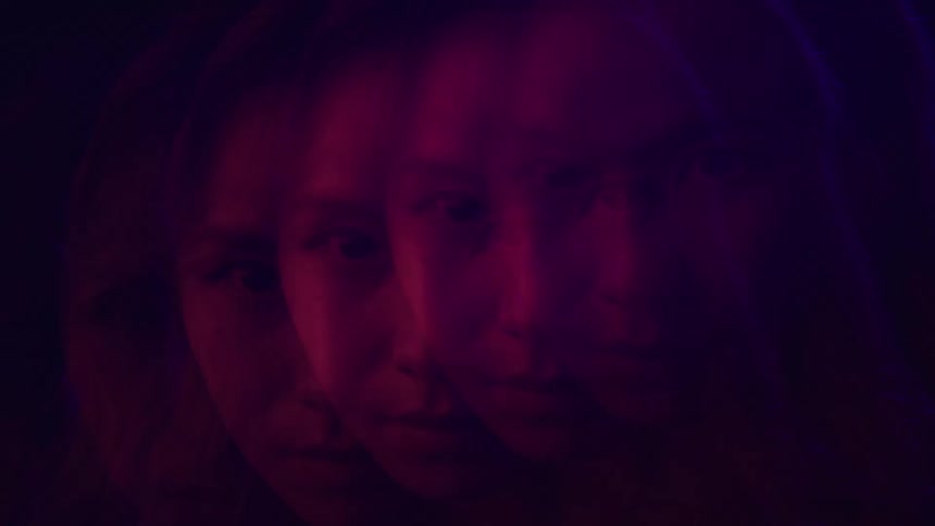 The video features a stylized shot of a womans face in a dark setting illuminated by red and blue light the video uses a splitimage effect to show multiple overlapping profiles and frontfacing views of her face simultaneously the womans expression