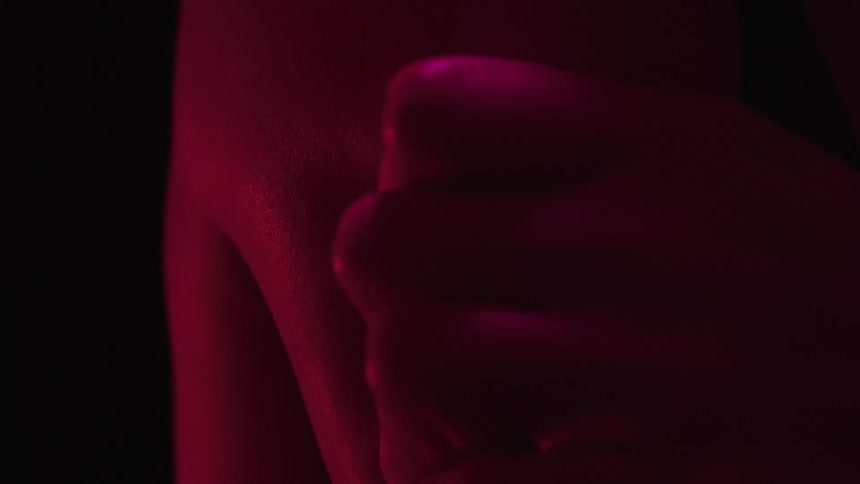 Hand grips an arm tightly under red lighting